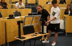 Radní Jindra Zalabáková si prohlíží princip fungování svářecí stolice s ručním a elektrickým ovládáním vyrobený žáky ze Střední školy technické v Mostě